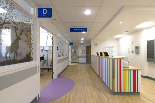A photo of the paediatrics ward at Addenbrooke's showing the window manifestations, vibrant reception desk and wayfinding signage.